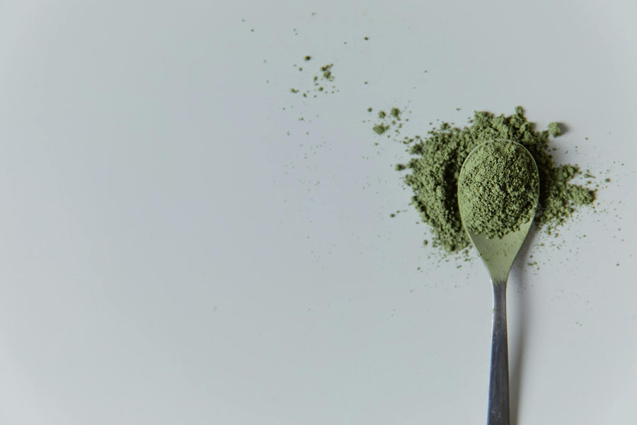 green kratom powder on a spoon|relaxed woman drinking tea