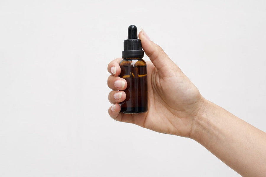 Woman’s hand holding a dropper bottle|