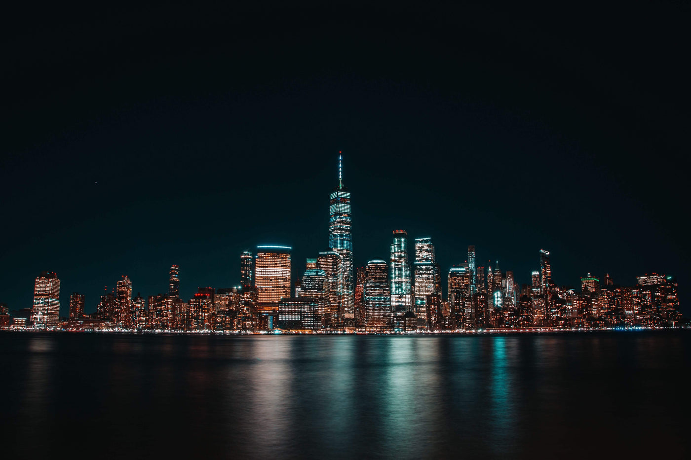 illuminated cityscape of Jersey City at night|stainless spoon with green kratom powder