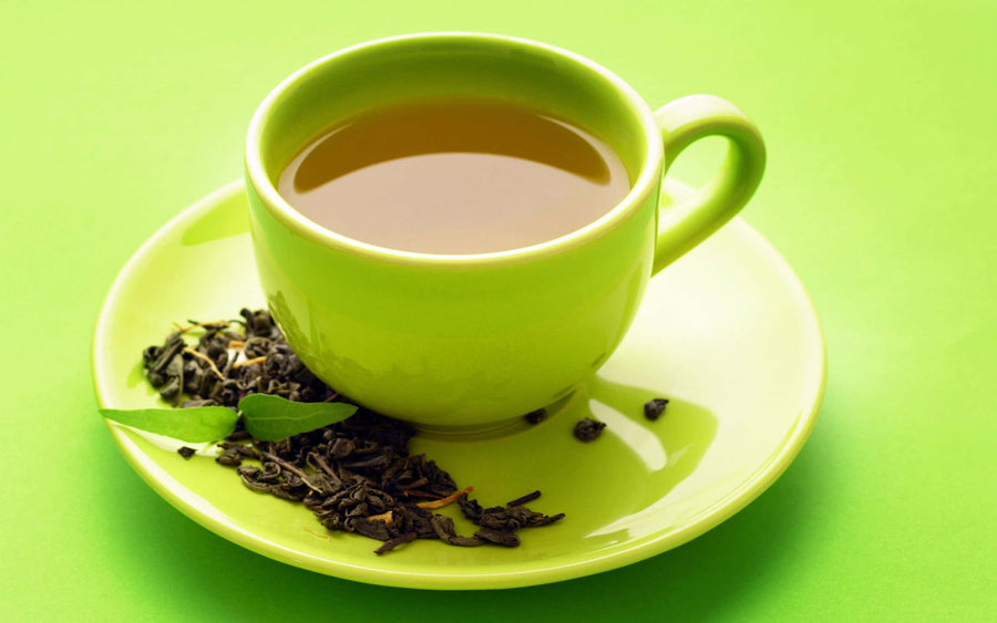 kratom tea in a cup|Tea in a light green cup with dried herbs on the saucer