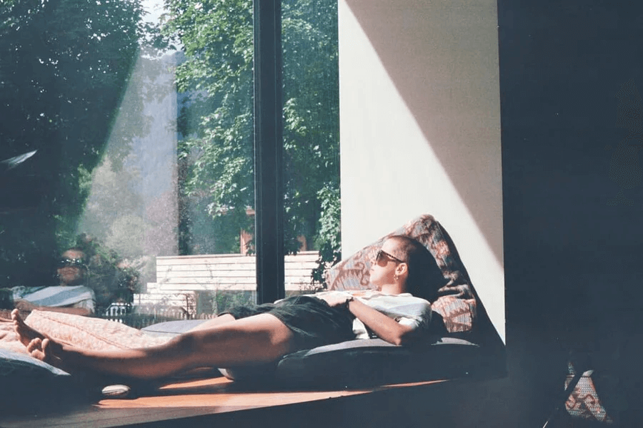 A person lying down and relaxing by a window