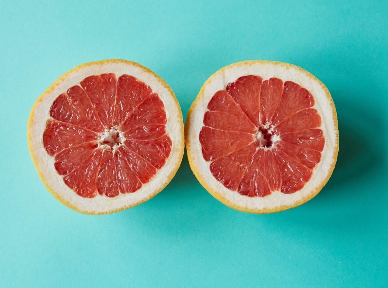 ripe sliced grapefruit placed on blue surface