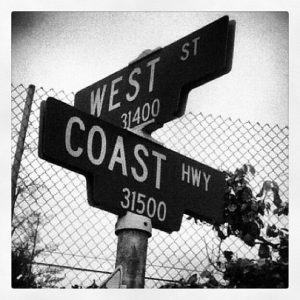 Greyscale image of street signs for West & Coast