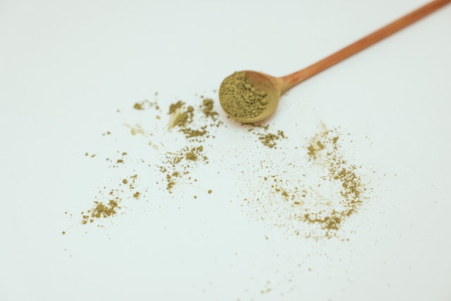 Red Bali kratom powder with wooden spoon