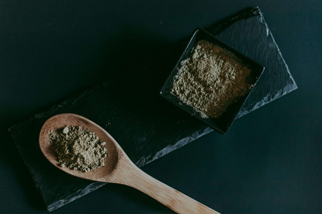 A spoon and bowl full of kratom powder