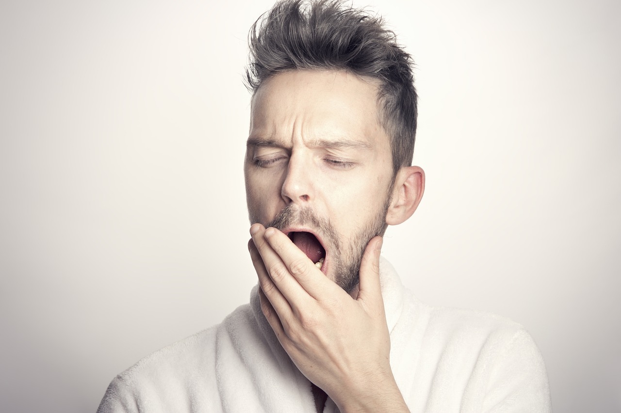 tired man yawning in front of a white background