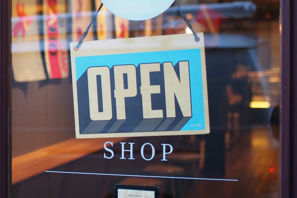 Open sign hanging on a glass shop entrance door