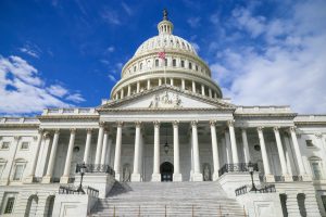 Panoramic photo of the U.S. Capitol Building beneath a cloudy sky.