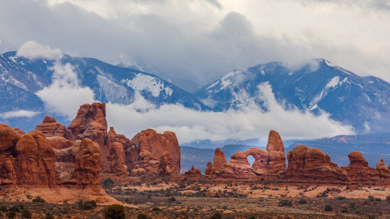 Towering red rocks against a mountain landscape in Moab, Utah