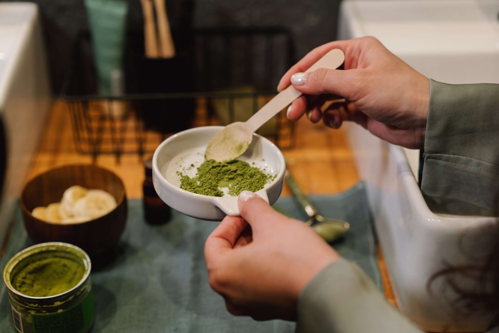 person holding a ceramic bowl with green powder